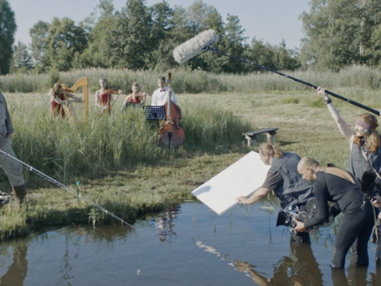 Ein Filmteam steht in einem Sumpf und filmt einen angelnden Mann.