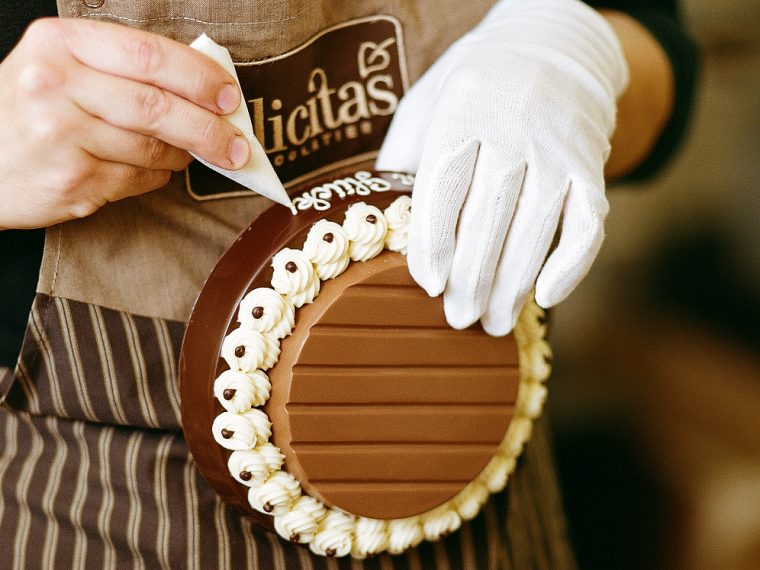 Eine Person verziert einen Schokoladensockel.