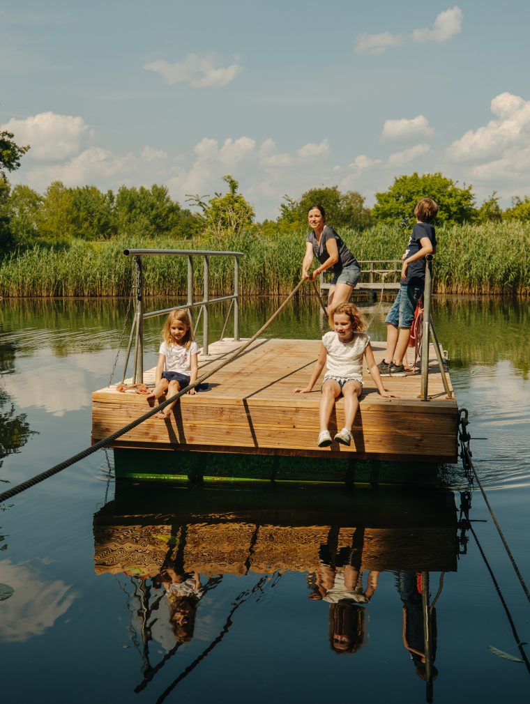 Eine Frau ist mit Kindern auf dem Wasser auf einem Floß.