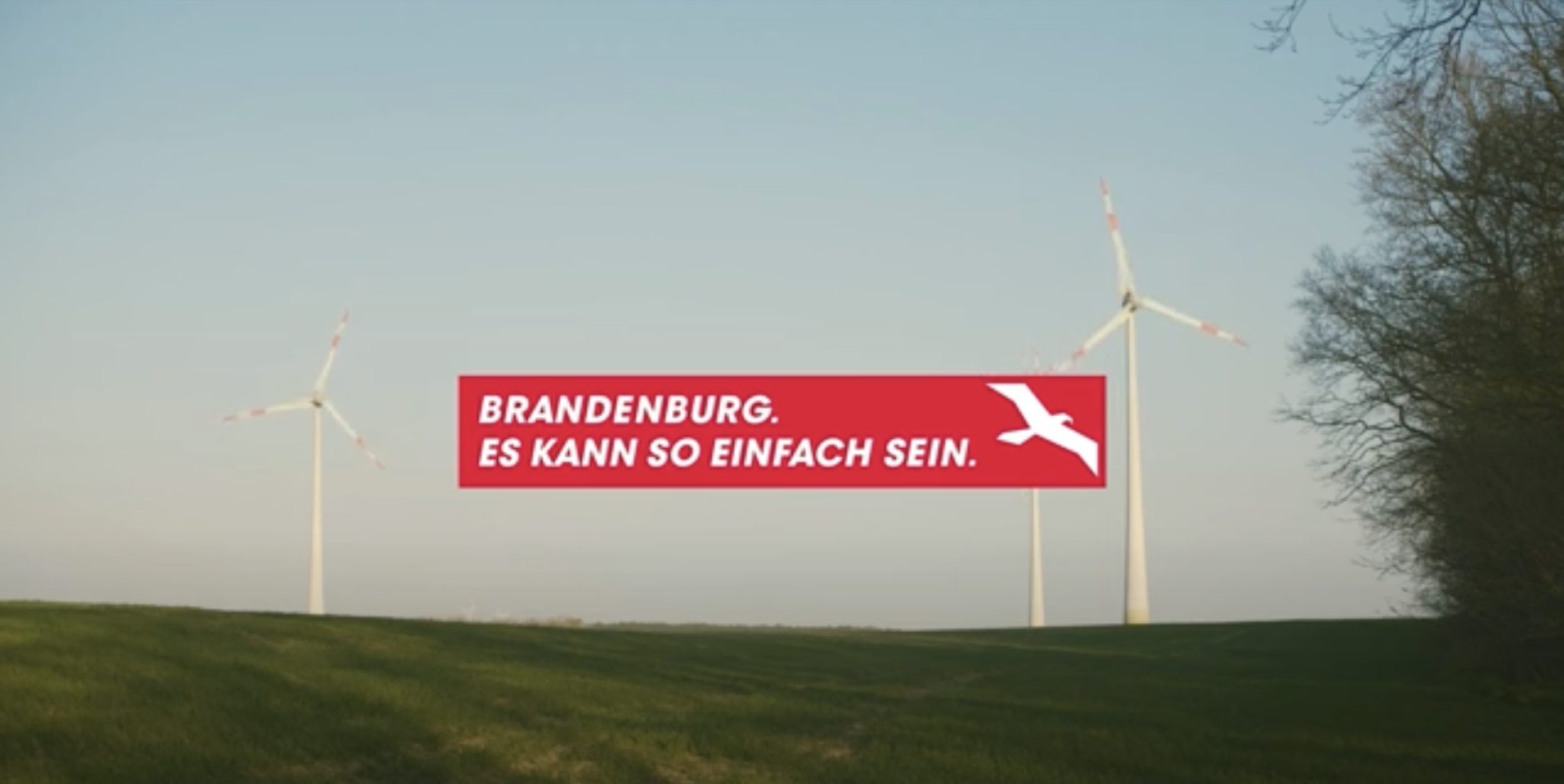 Eine Wiese mit drei Windrädern und der Aufschrift "Brandenburg. Es kann so einfach sein"