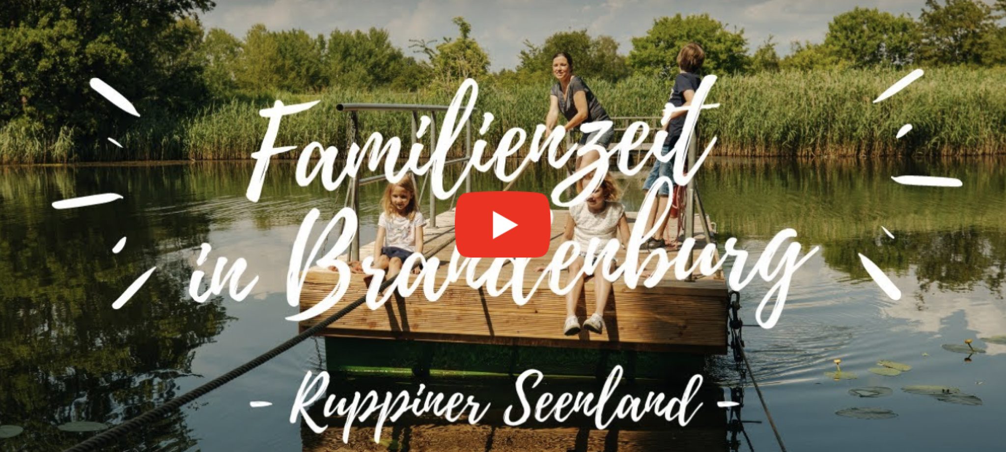 Eine Familie macht eine Floßfahrt auf einem See. Im Hintergrund sind Bäume. Eine Aufschrift "Familienzeit in Brandenburg. Ruppiner Seenland"