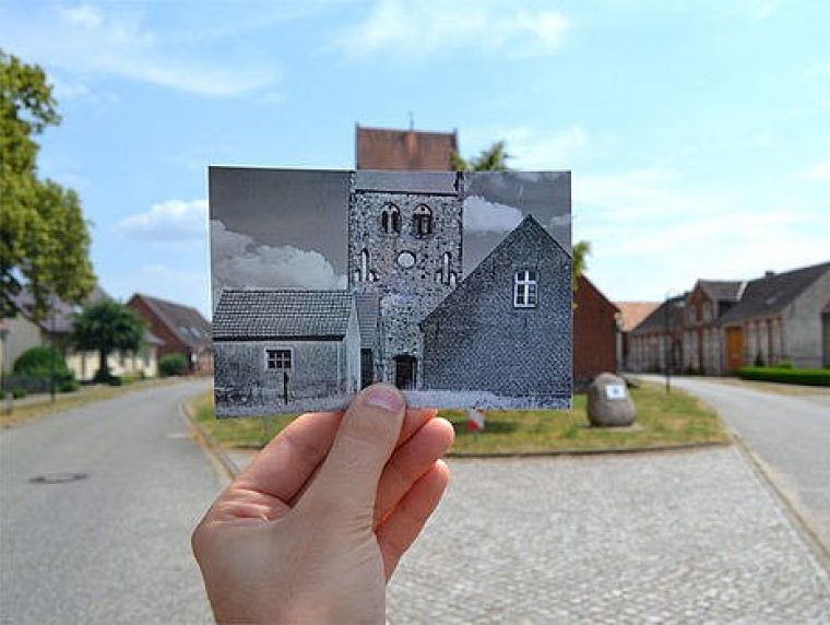 Eine Hand hält ein ausgedrucktes Foto aus dem Film "Das weiße Band" vor einer alten Dorfstraße.