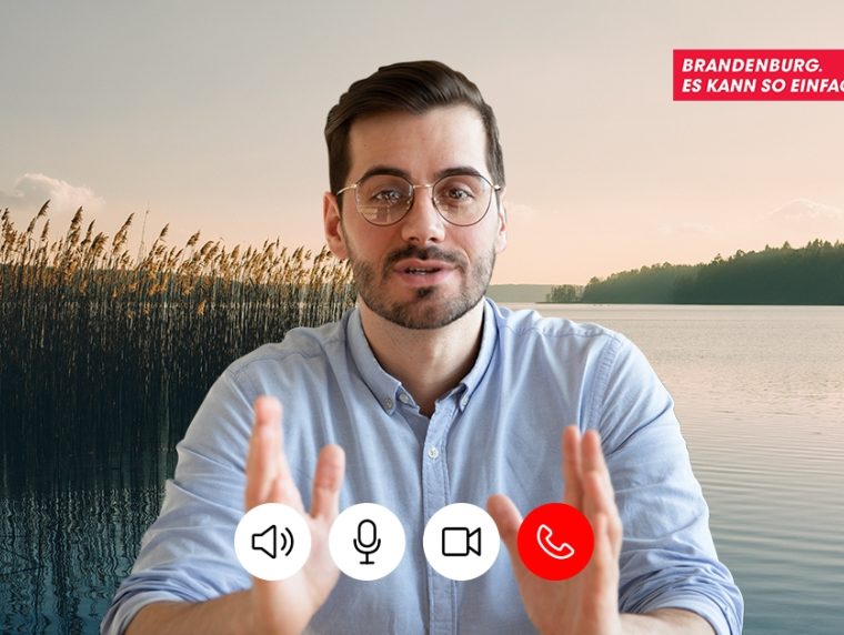 Ein Mann in einem Videocall. Im Hintergrund ein See und Wald. Im oberen rechten Eck ein rotes Logo mit der Schrift "Brandenburg. Es kann so einfach sein."