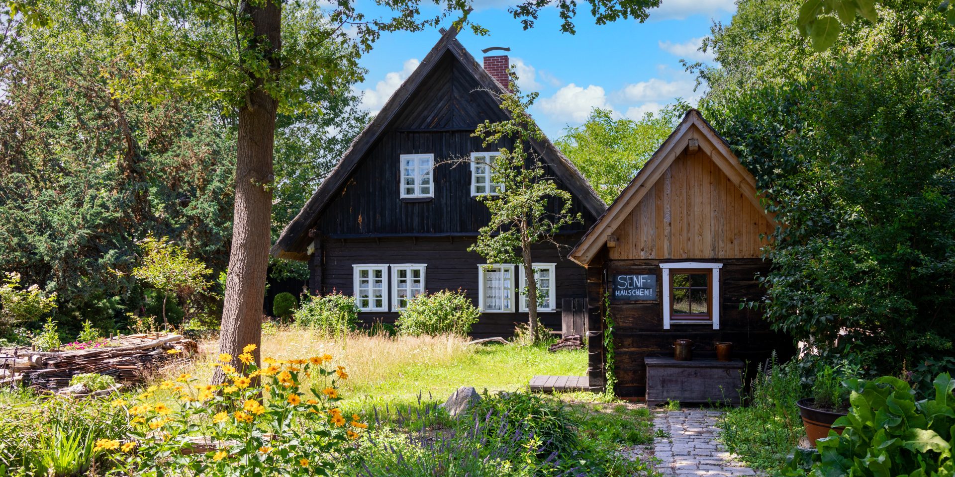 Ein kleines Holzhaus mit Garten und einem Schuppen davor.
