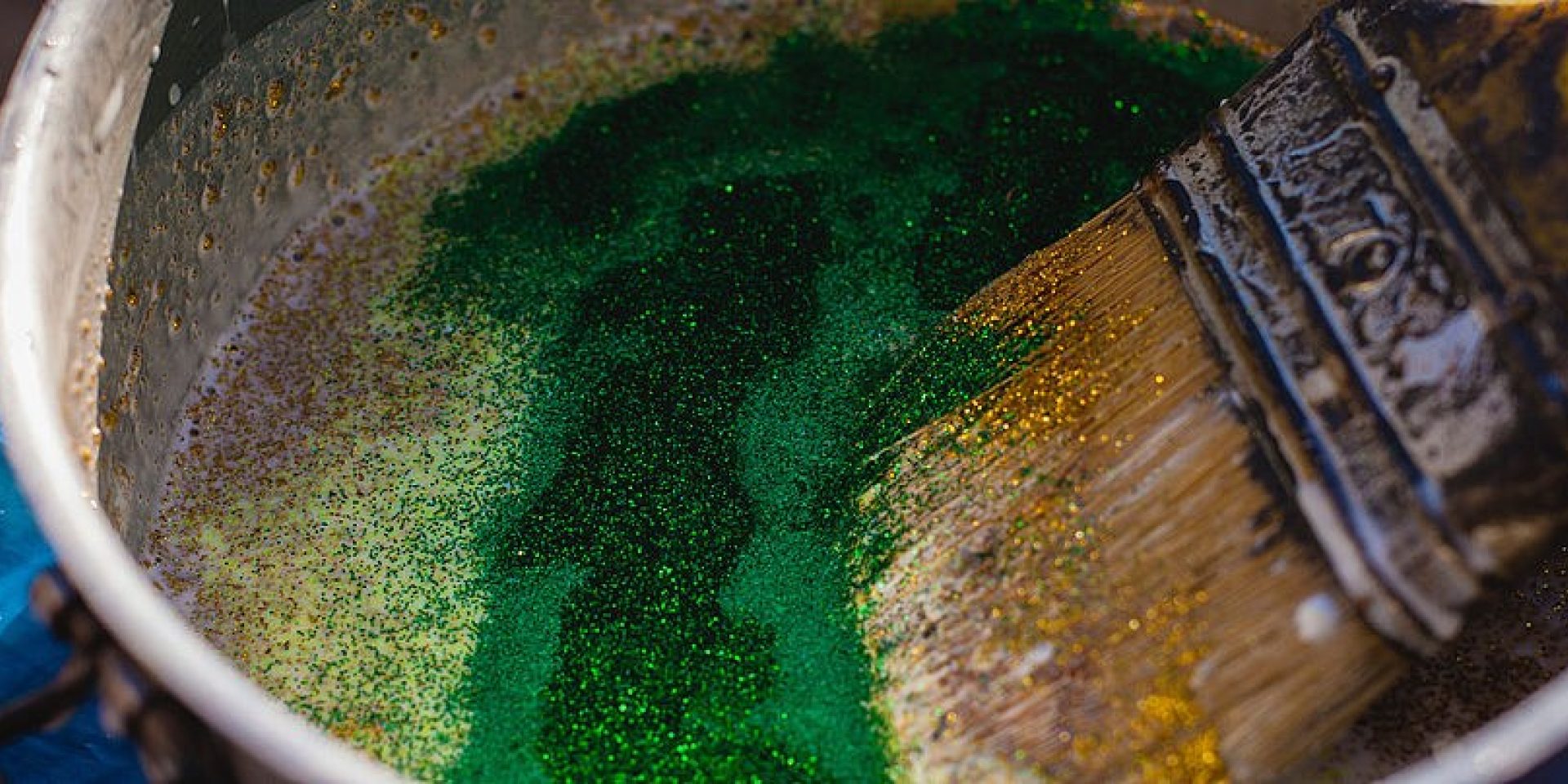 Ein Pinsel in einem grünen Farbeimer.