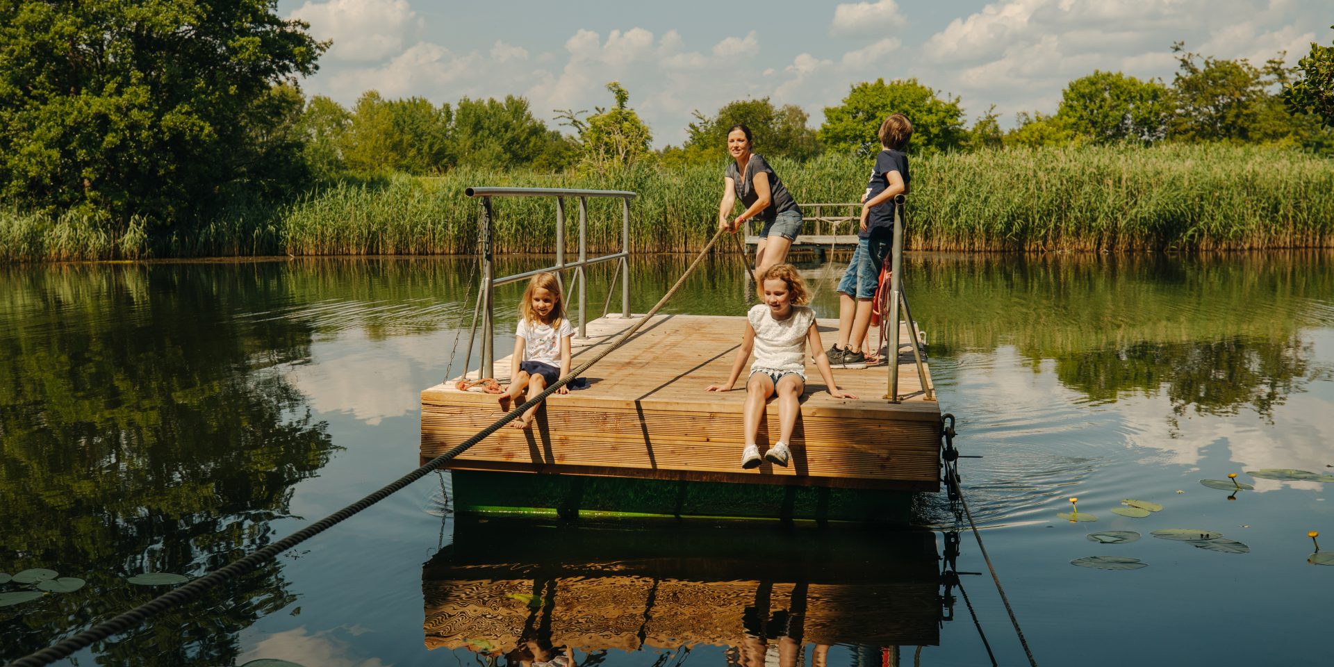 Eine Frau ist mit Kindern auf dem Wasser auf einem Floß.