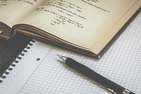 Ein Notizbuch und ein Stift neben einem Schreibblock.